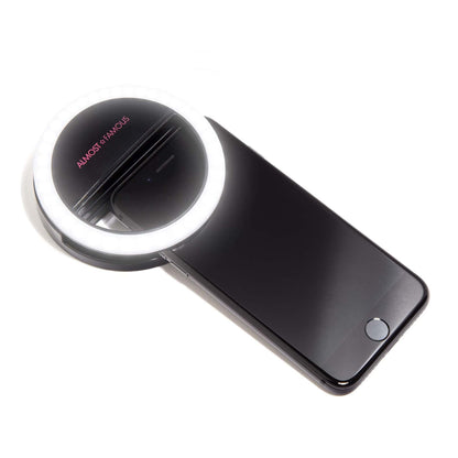 Spotlight Selfie Light showing a white LED ring light clipped onto a black smartphone with a reflective surface and screen on.