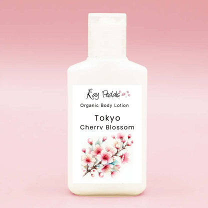 12 oz white plastic bottle of Tokyo Cherry Blossom organic body lotion with floral label and pink cherry blossom illustration