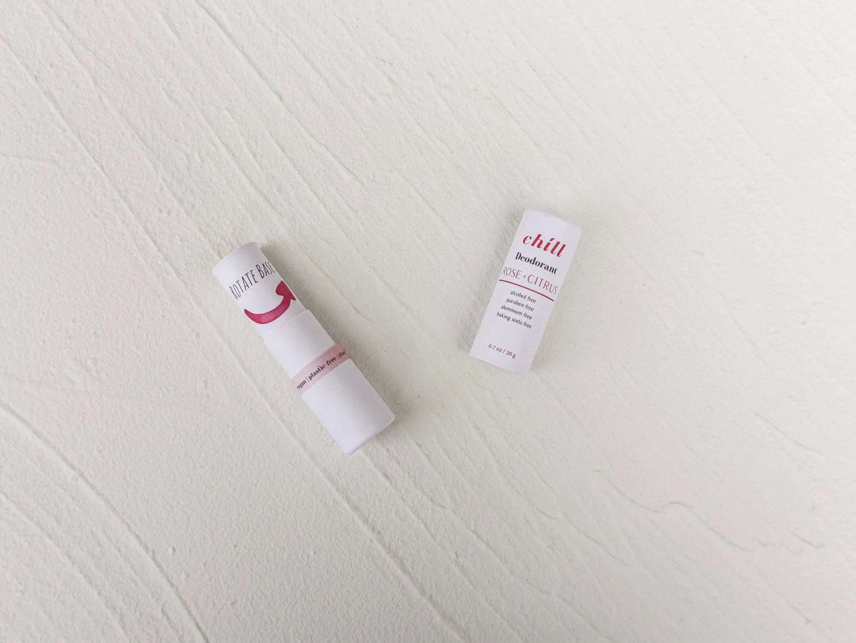 Natural Deodorant Stick with white paper packaging featuring rose and citrus text and minimalistic design on a light surface.