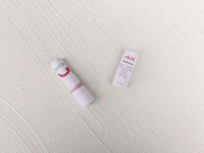 Natural Deodorant Stick with white paper packaging featuring rose and citrus text and minimalistic design on a light surface.