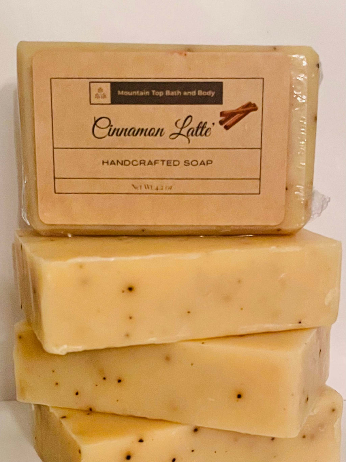 Stack of light beige handcrafted soap bars with small dark specks and a label reading Cinnamon Latte on top bar, Cinnamon Latte scented.