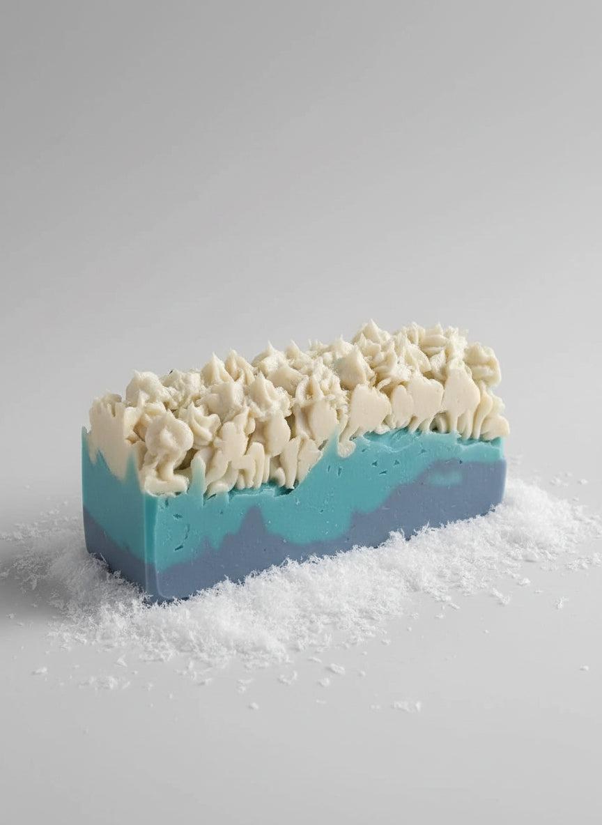 Winter Blue Soap bar with layered blue and teal hues topped with textured creamy white swirls and snow-like flakes beneath.